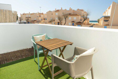 Balcón de Tarifa Cozy House con mobiliario exterior y vistas despejadas al mar, rodeada de edificios mediterráneos.