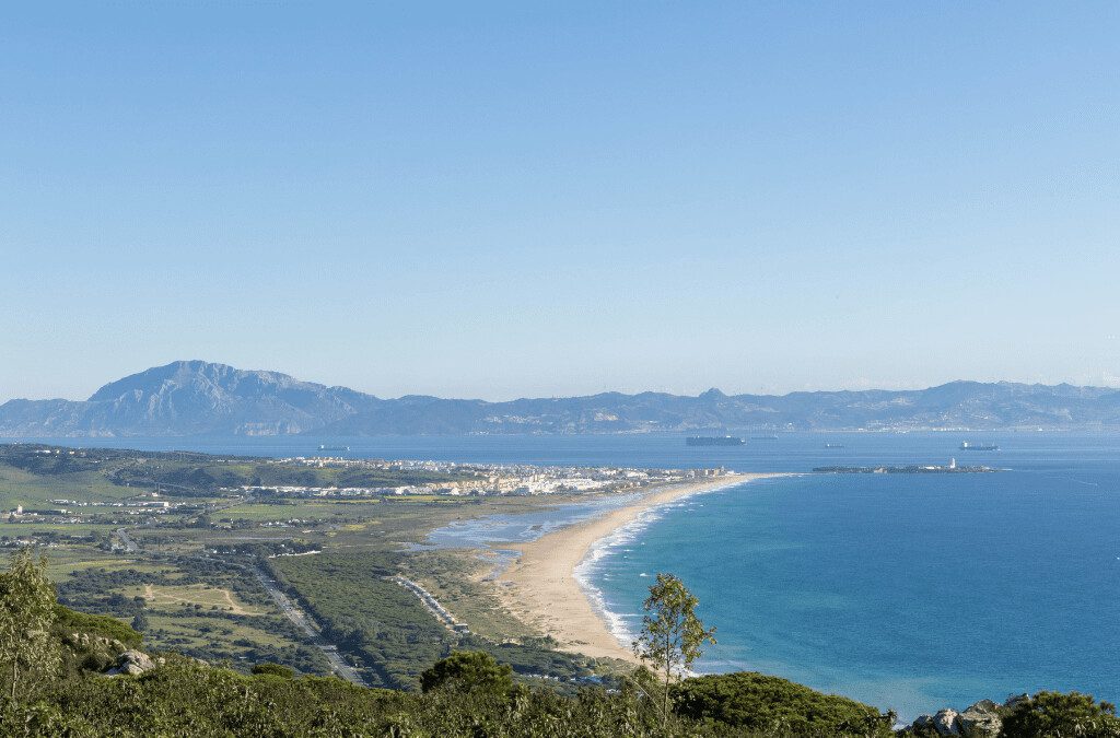 Vista de Tarifa desde La Peña – Mirador con panorámica del Estrecho y la costa africana. Vista panorámica de Tarifa desde La Peña con la playa de Los Lances y el Estrecho de Gibraltar al fondo. Un mirador natural con vistas espectaculares del mar Mediterráneo y Marruecos. Imagen de Tarifa vista desde la montaña de La Peña, con la playa de Los Lances y el Estrecho de Gibraltar al fondo. Se observa el mar azul y la costa africana en la distancia